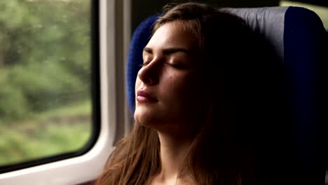 aim footage of a gorgeous young woman travelling by train. have a nap. closed eyes. sitting near the window. long haired brunette