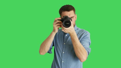 mid shot of a handsome photographer taking pictures. background is green screen.
