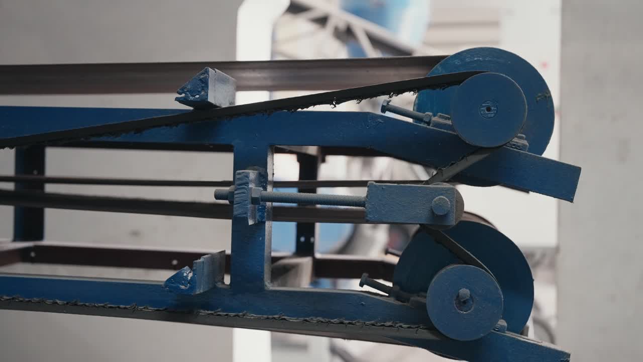 공장 기계에서 회전하는 파란색 풀리와 컨베이어 벨트의 클로즈업 뷰