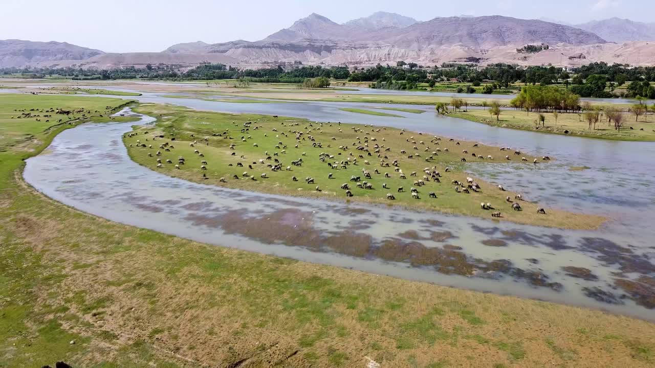 Aerial drone view of a river winding through a lush, rugged mountain valley in Kabul, Afghanistan