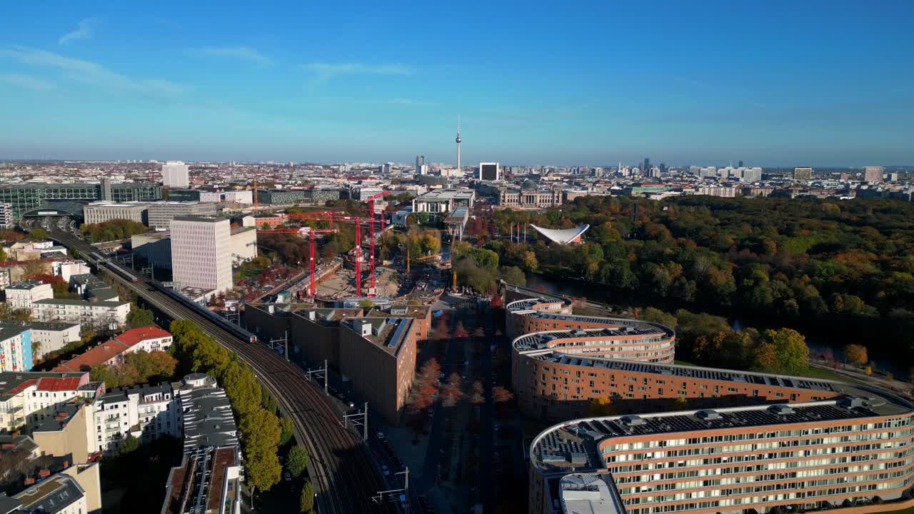 Scenic view of a train crossing a bridge over a river in berlin, surrounded by vibrant autumn foliage. Gorgeous aerial view flight ascending drone