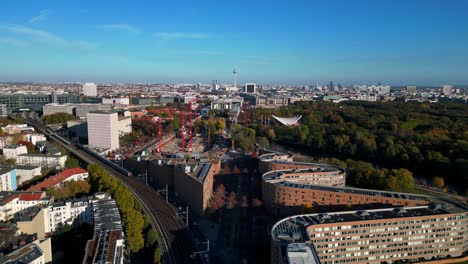scenic view of a train crossing a bridge over a river in berlin, surrounded by vibrant autumn foliage. gorgeous aerial view flight ascending drone