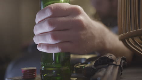 Hand-Auf-Flasche-Neben-Waffe-In-Nahaufnahme,-Schlafender-Betrunkener-Mann-Unscharf