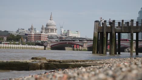 waves lap in slow motion on the shore of the river thames with st. paul's cathedral in the background
