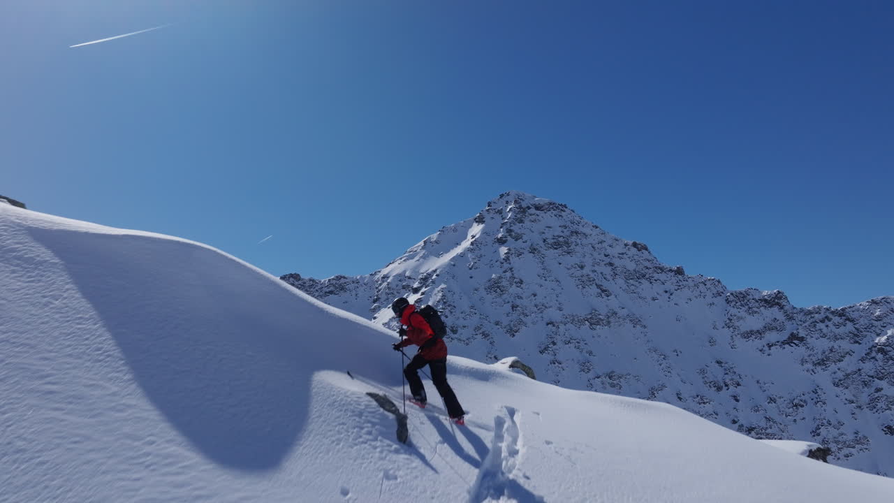 A professional skier hikes up a steep ridge in Verbier, then drops into an epic freeride descent. Pure adventure skiing in deep snow, dramatic terrain, and breathtaking alpine scenery.