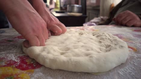 mujer con las manos desnudas haciendo masa para un pan georgiano plano, de cerca