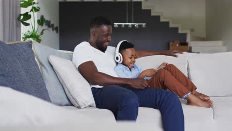 African-american-father-and-son-using-a-digital-tablet-together-with-boy-wearing-headphones