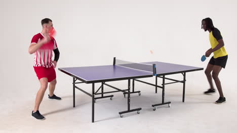 multiracial male table tennis players serving and passing the ball to each other on white background