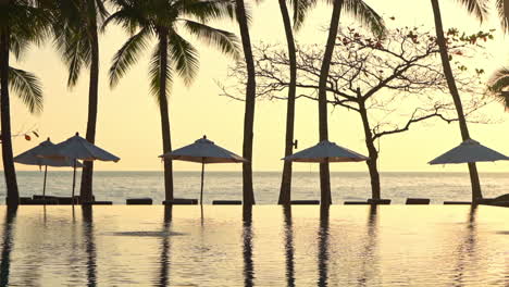 A-golden-setting-sun-reflects-in-the-waters-of-a-luxury-resort-swimming-pool