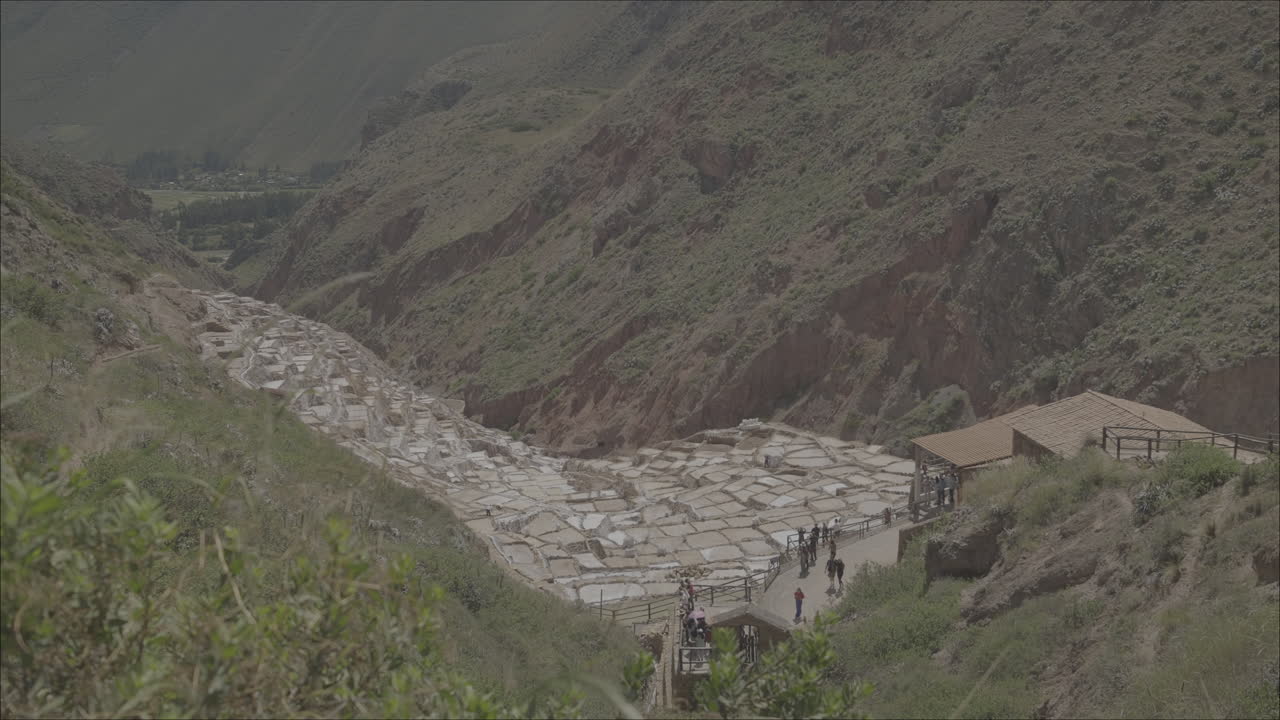 Moving shot looking down on the Maras Salt Mines in Peru on a cloudy day LOG
