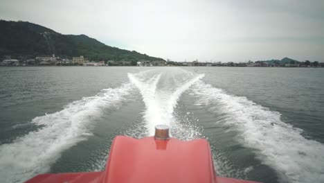 motor boat cruising on the calm ocean and leaving water trail in kyoto, japan. - wide shot