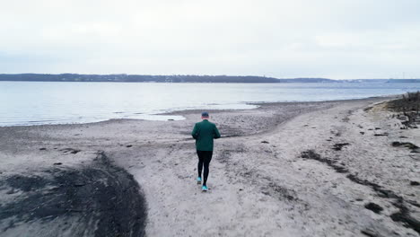 lone person jogging on a desolate winter beach on overcast day