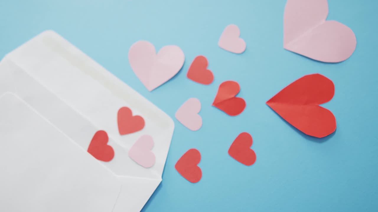 Envelope with red and pink paper hearts at valentine's day on blue background