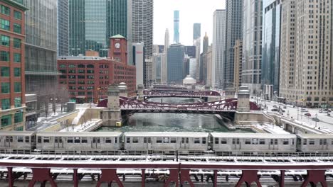 aerial pullback reveals train crossing chicago river in winter