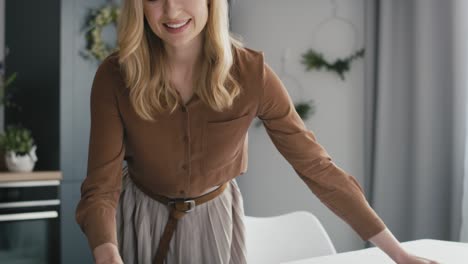 caucasian woman laying a white tablecloth on the table.