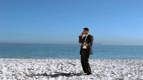 businessman throwing his mobile in the air on the beach