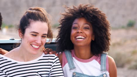 friends on a trip sitting in car trunk at roadside, close up