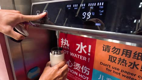 person adjusting water temperature on digital dispenser