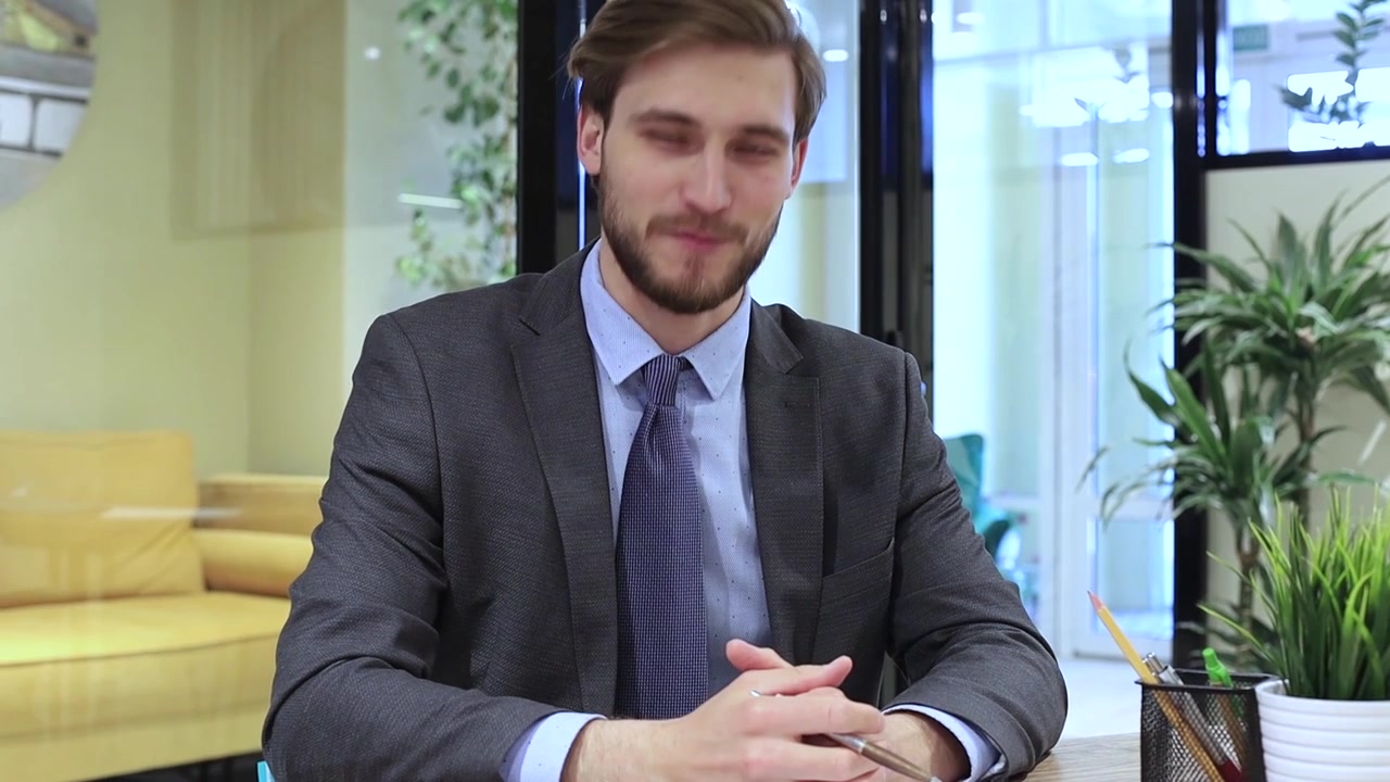 Uomo d'affari che parla e gesticola in un ambiente d'ufficio moderno.