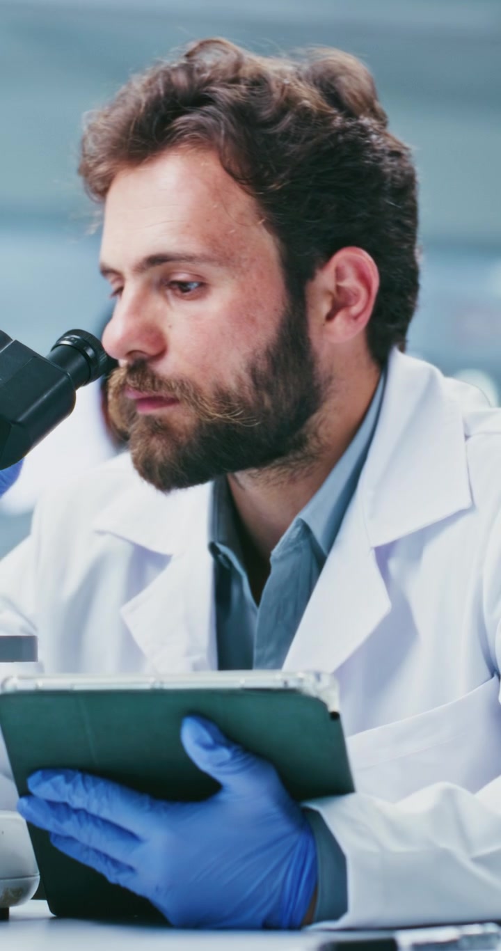Scienziato che usa tablet e microscopio in laboratorio