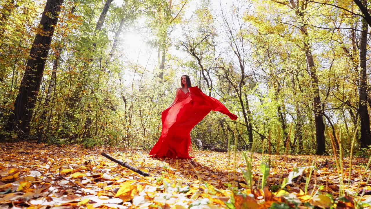 A Beautiful Dance in Nature: Captivating Moments of Elegance and Joy as the Dancer Swirls in a Vibrant Red Dress Amongst Golden Autumn Leaves