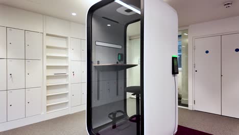 futuristic soundproof pod in a modern office providing a quiet workspace for concentration and privacy near lockers and shelves