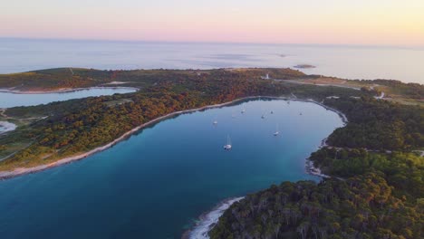 una impresionante vista de avión no tripulado muestra una isla perfectamente ubicada en el corazón de un mar azul brillante, ocupada con barcos turísticos