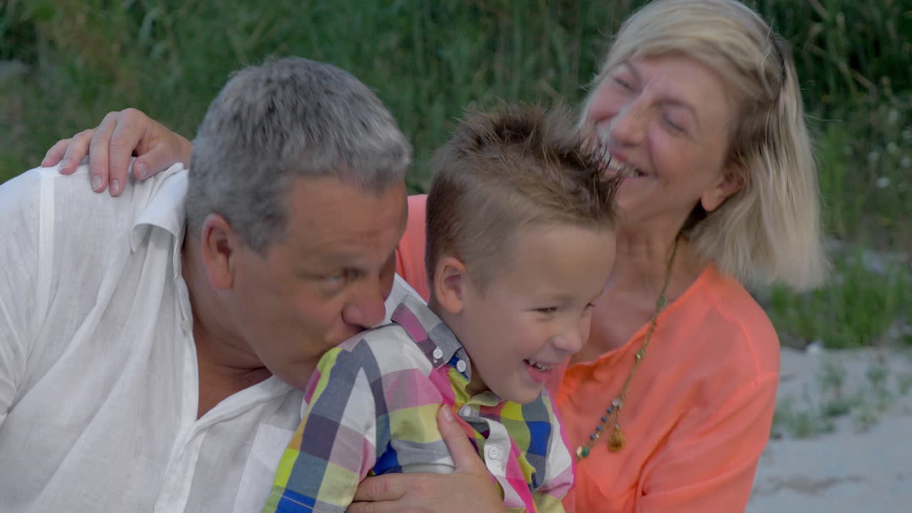 дедушка и бабушка целуют дорогого внука.