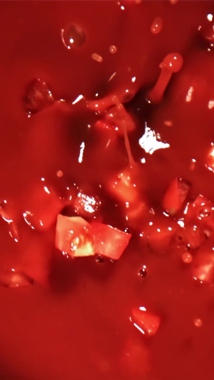 Rallentatore di pomodori a cubetti che schizzano nella salsa rossa