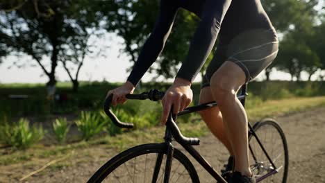 unrecognizable cyclist rides bicycle along the asphalt road, close up