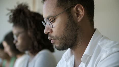 Focused African American man in eyeglasses looking down