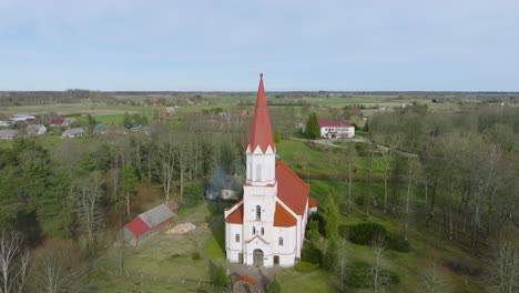 aerial view of a white church with red roof on a sunny spring day, wide angle shot moving forward