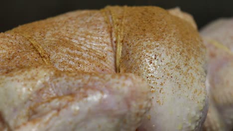 close up pan right of raw chicken being spiced, tied to skewer