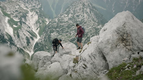 Dos-Excursionistas-Se-Encuentran-En-Las-Montañas,-Uno-Le-Da-A-Otro-Algo-En-La-Mano