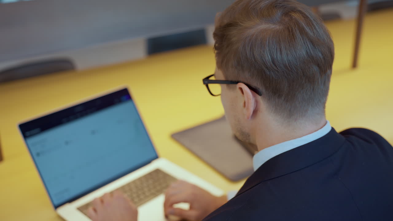gerente corporativo en traje de negocios escribiendo en una computadora portátil sentado en el lugar de trabajo - primer plano trasero
