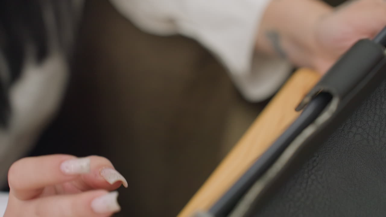 aerial view of hand with manicured nails engaging in digital communication on tablet with blurred background and soft bokeh lights creating calm remote work environment