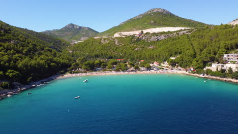 people on tourist campground with pebbled and sandy beach in prapratno bay in croatia adriatic coast