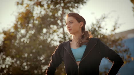 Low-angle-medium-dolly-shot-of-beautiful-young-fit-caucasian-woman-in-her-jogging-outfit,-looking-to-her-right-with-an-expression-of-satisfaction-and-confidence