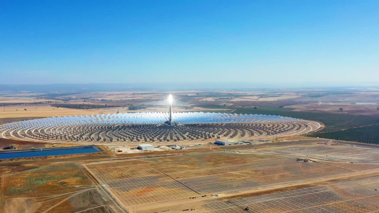 Large solar thermal plant uses mirrors that focus the sun's rays on a collection tower to produce renewable and pollution-free energy - aerial view with a drone