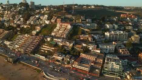 Aerial-view-across-Reñaca-Chile-resort-buildings-on-golden-sunrise-beach-coastline