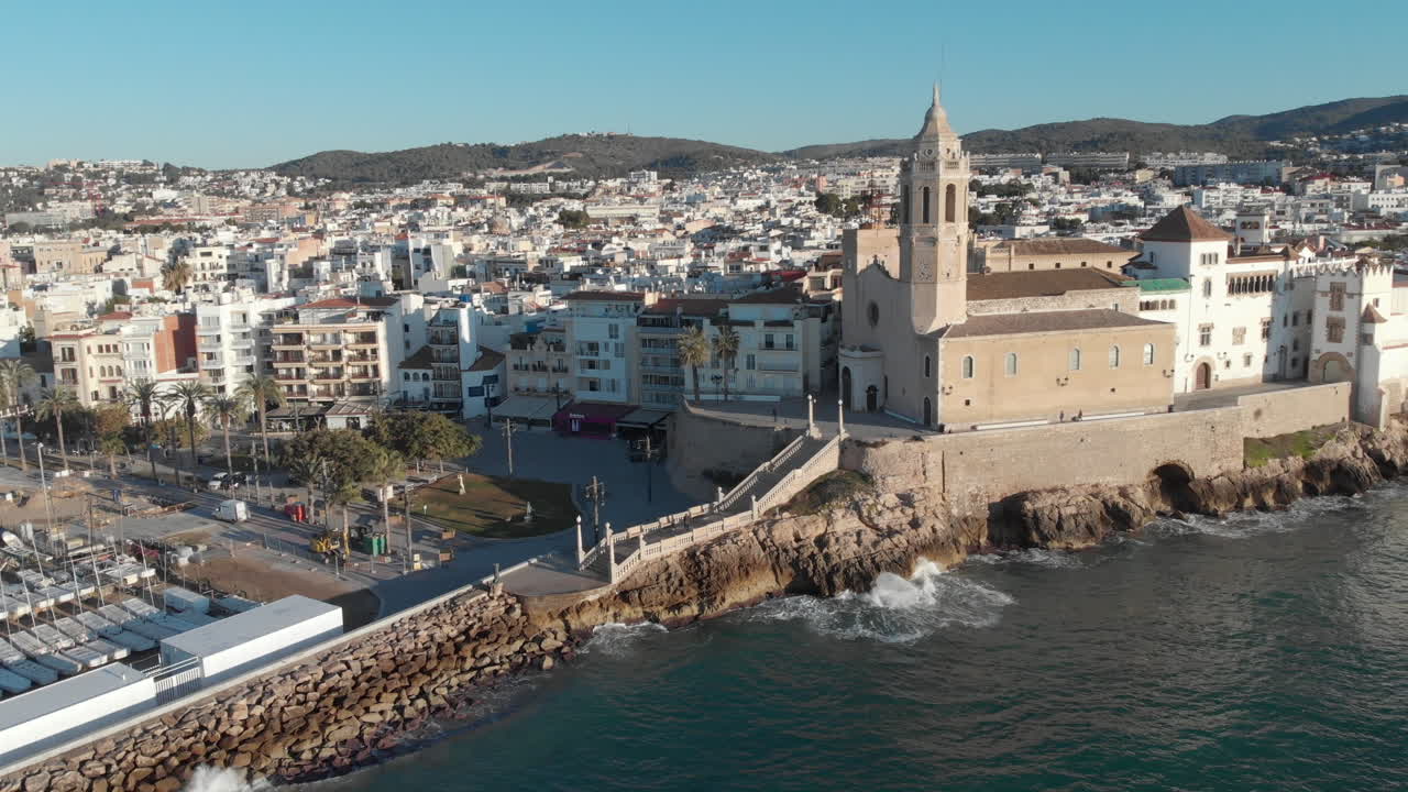 la antigua iglesia de piedra se encuentra en la costa, rodeada de casas, mientras las olas chocan contra sus paredes