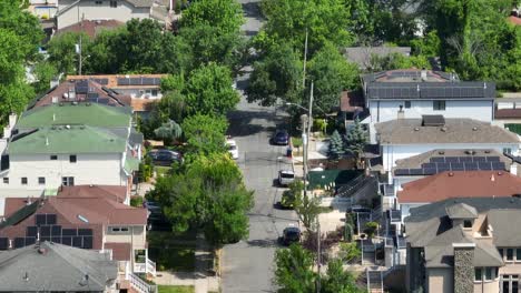 aerial tilt up shot of american residential area with solar panels installed on roof and beautiful tree avenue - zoom shot