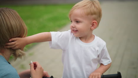 a joyful outdoor moment between a mother and her son, as the little boy playfully touches his mother s hair