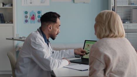 doctor explaining medical data to patient on laptop