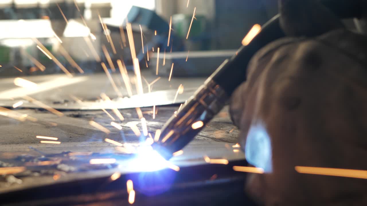 Welder on the table welds a set of metal parts