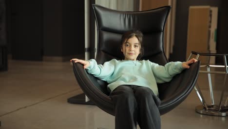 a toddler beautiful girl is spinning on a comfortable leather office chair a toddler beautiful girl is spinning on a comfortable leather office chair happy childhood concept