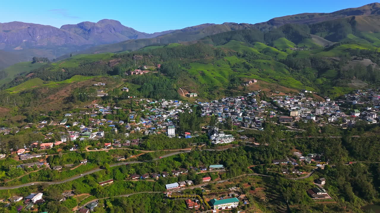 Establishing drone shot overlooking homes in Munnar hill station, in sunny India