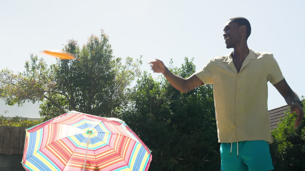 Diverse friends enjoying sunny day by pool with colorful umbrella, laughing and relaxing
