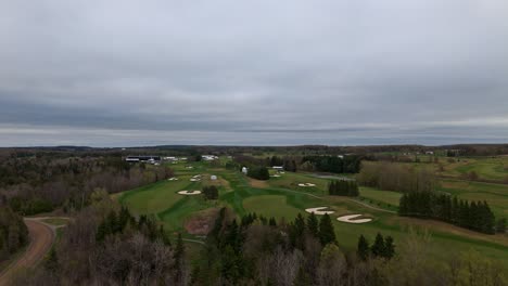 sand bunker and green golf course field in spring season. rising drone wide shot. cloudy day im alton, toronto, canada.
