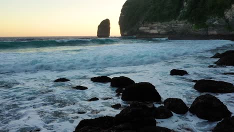 Luftaufnahme-Von-Großen,-Kleinen-Felsen-Und-Schwarzem-Strand,-Der-Vom-Blauen-Wasser-Des-Ozeans,-Nusa-Penida,-Bali,-Indonesien,-Umspült-Wird